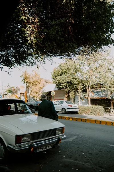 عکس مردی در حال پیادهروی در کنار یک خودروی پیکان سفید در کنار جاده