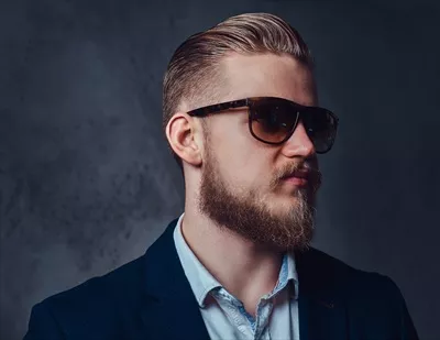 عکس مرد خوشتیپ با ریش بلوند و کت و عینک آفتابی در حالتی شیک