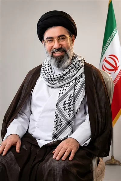 عکس سید مجتبی خامنه‌ای در حال نشسته کنار پرچم ایران